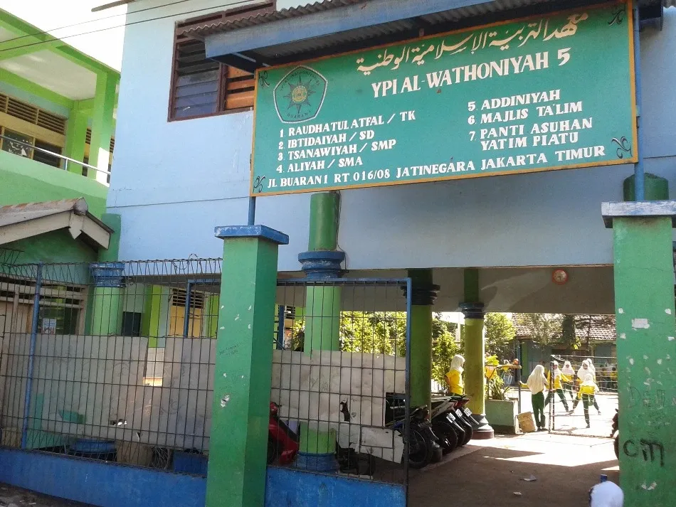 Gerbang YPI Al Wathoniyah 5 dengan papan nama unit RA, MI, MTs, MA, Diniyah, Majelis Taklim, dan Panti Asuhan